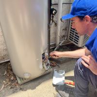 Rhys Brisbane plumber working on an electric hot water system heater