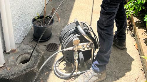Plumber using hydro jet to unblock outdoor stormwater drain