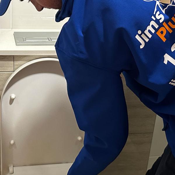 Plumber using a plunger to iunblock a toilet