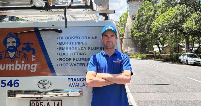 Plumber in front of van with Spring Hill windmill Brisbane in background