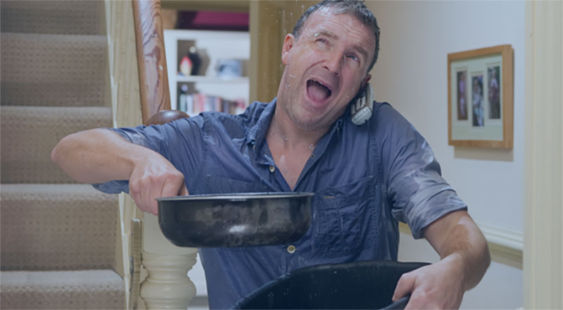 Man holding pots catching water from leaking roof