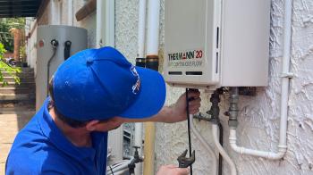 Plumber fixing a tankless hot water system outside