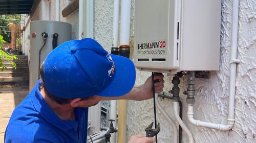 Plumber fixing a tankless hot water system outside