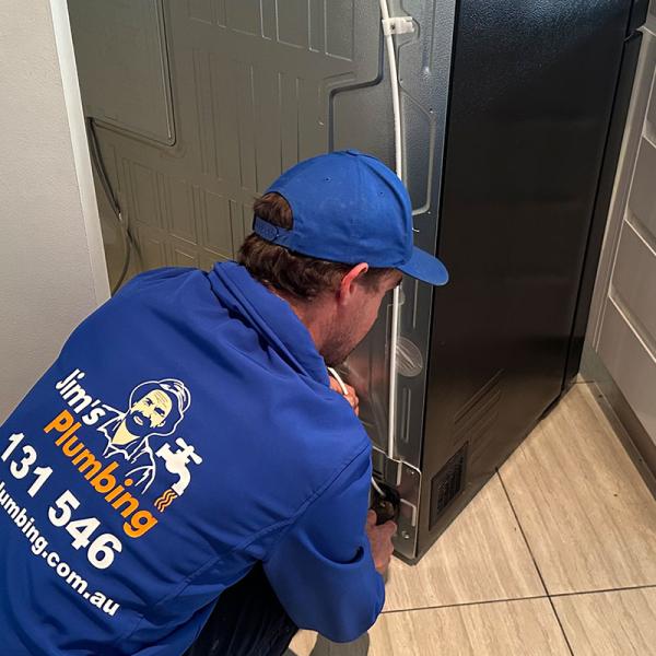 Plumber hooking up a new fridge to water mains