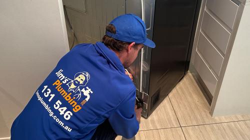 Plumber hooking up a new fridge to water mains