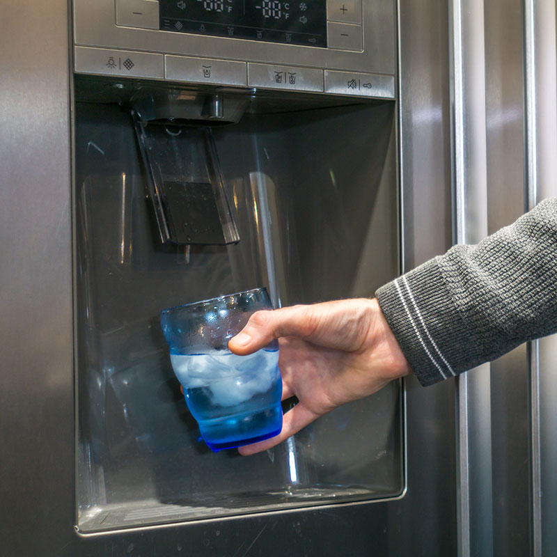 Closeup of fridge dispensing water from chiller