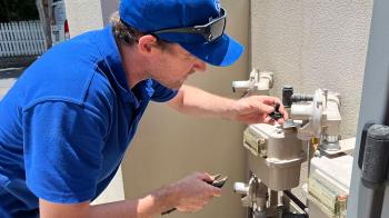 Plumber working on mains gas box at front of unit block