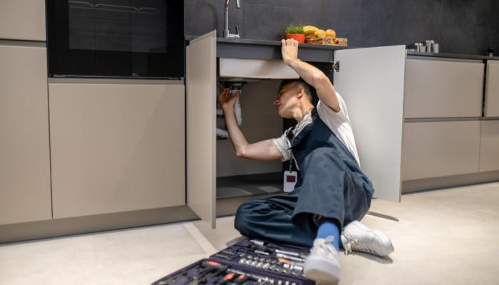 Man under kitchen sink plumbing