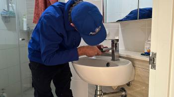 Plumber fixing a leaking tap in bathroom sink