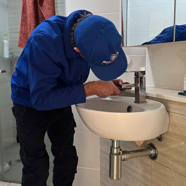 Plumber fixing a leaking tap in bathroom sink
