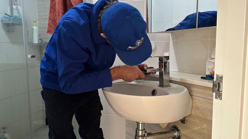 Plumber fixing a leaking tap in bathroom sink
