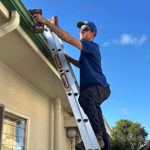 Plumber on ladder working on roof