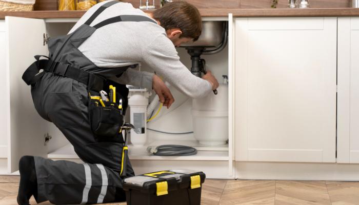 PLumber under kitchen sink fixing drain